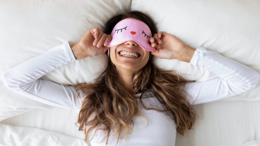 Top view happy woman wearing funny sleeping mask